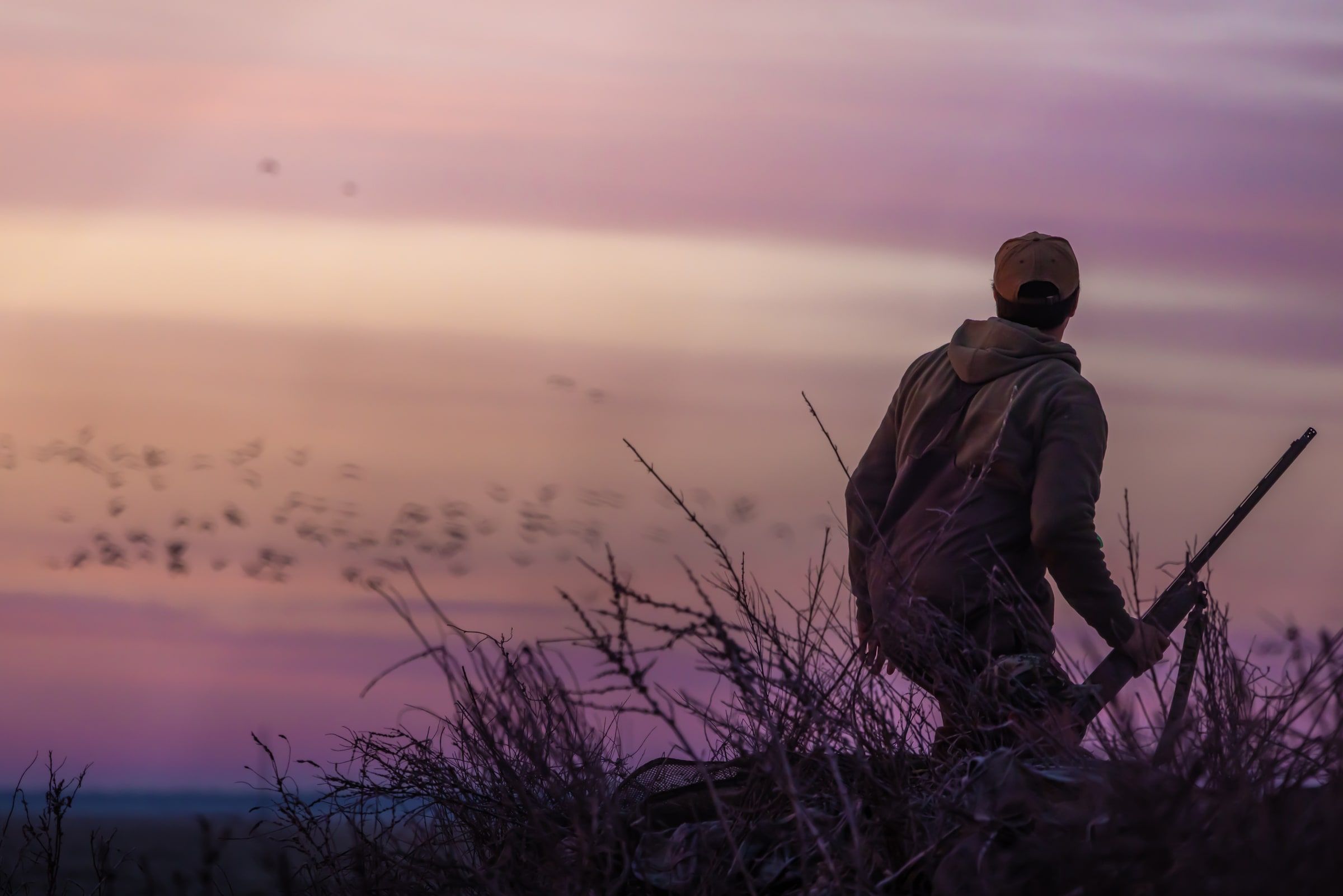 Hunter holding a shotgun at first light during a Delta Outdoors Co. waterfowl hunt.