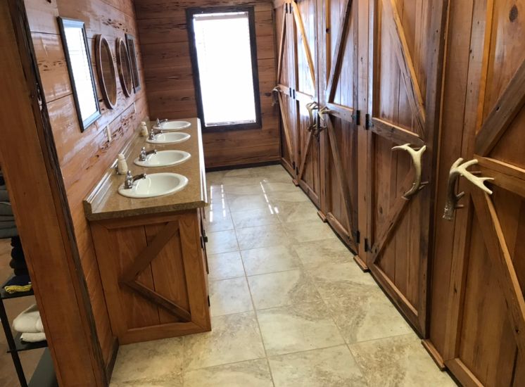 Delta Outdoors Co. lodge bathroom with wood stalls and multiple sinks for group trips.