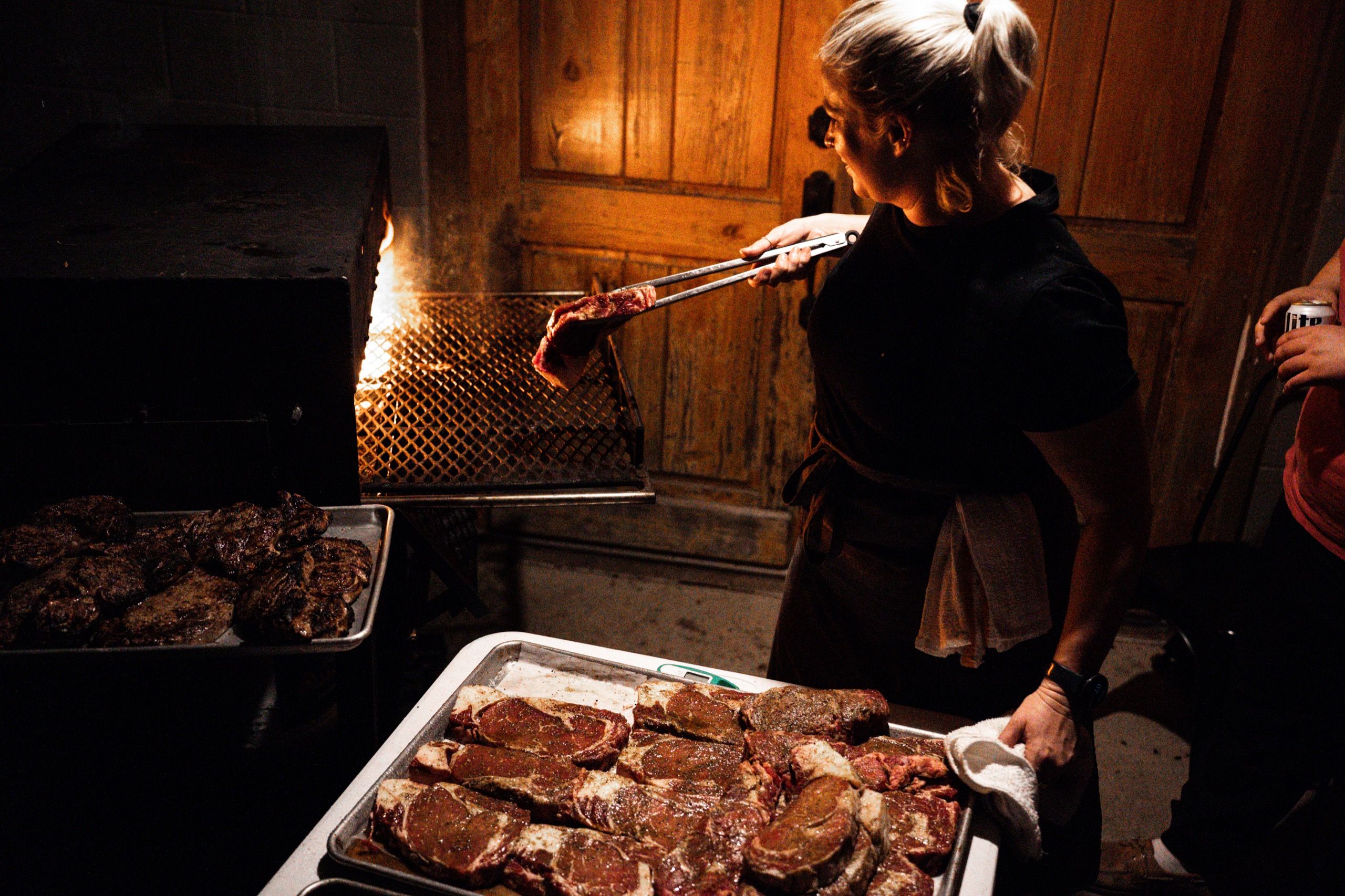 Lodge chef grilling steaks over an open flame for Delta Outdoors Co. guests.