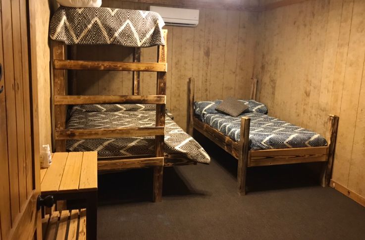 Delta Outdoors Co. lodge guest bunk room with wood beds for overnight hunting groups.