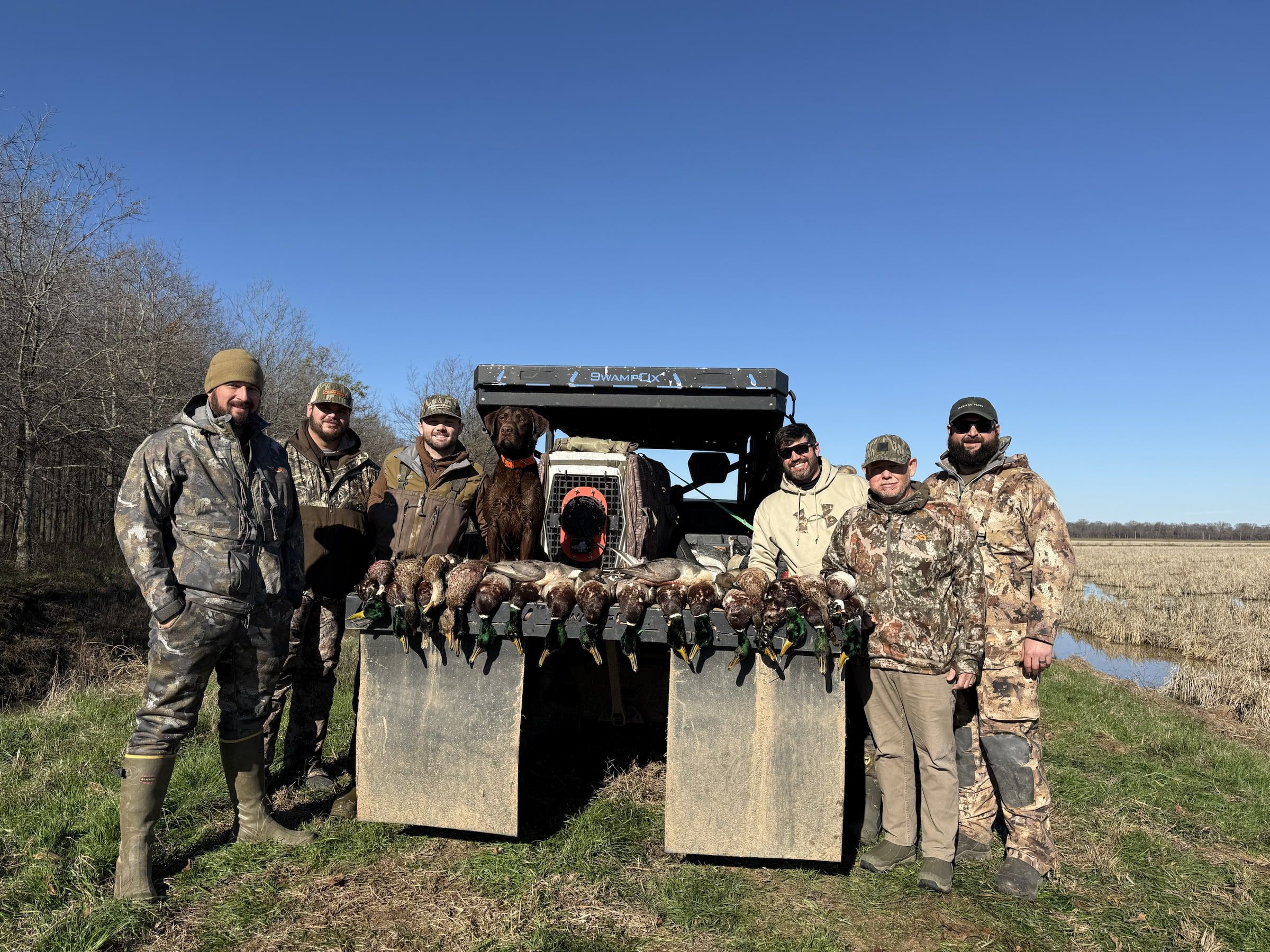 Delta Outdoors guests posing with a bird rack in an Arkansas field after a hunt.