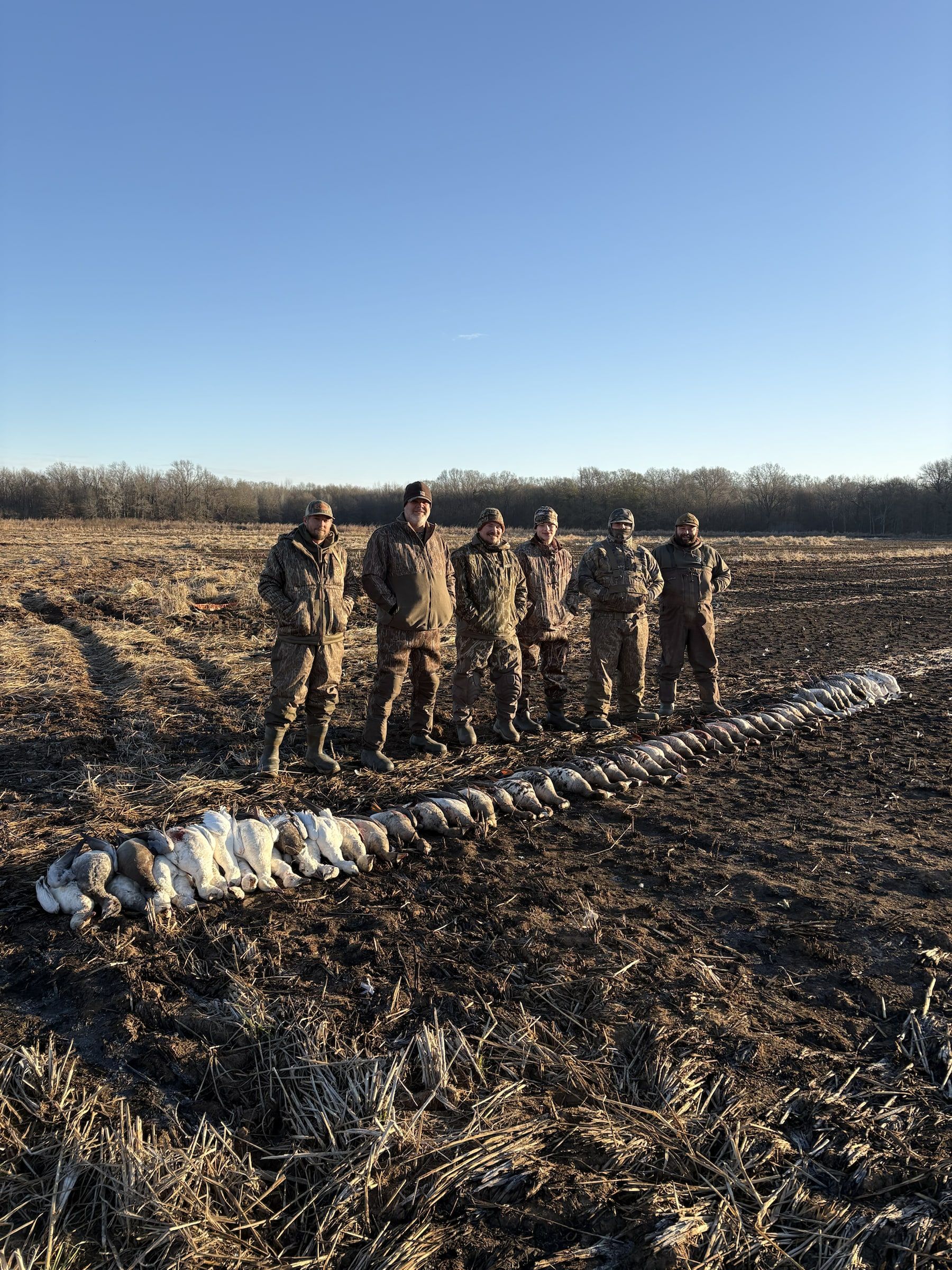 Delta Outdoors guests standing beside a long line of ducks in a field.