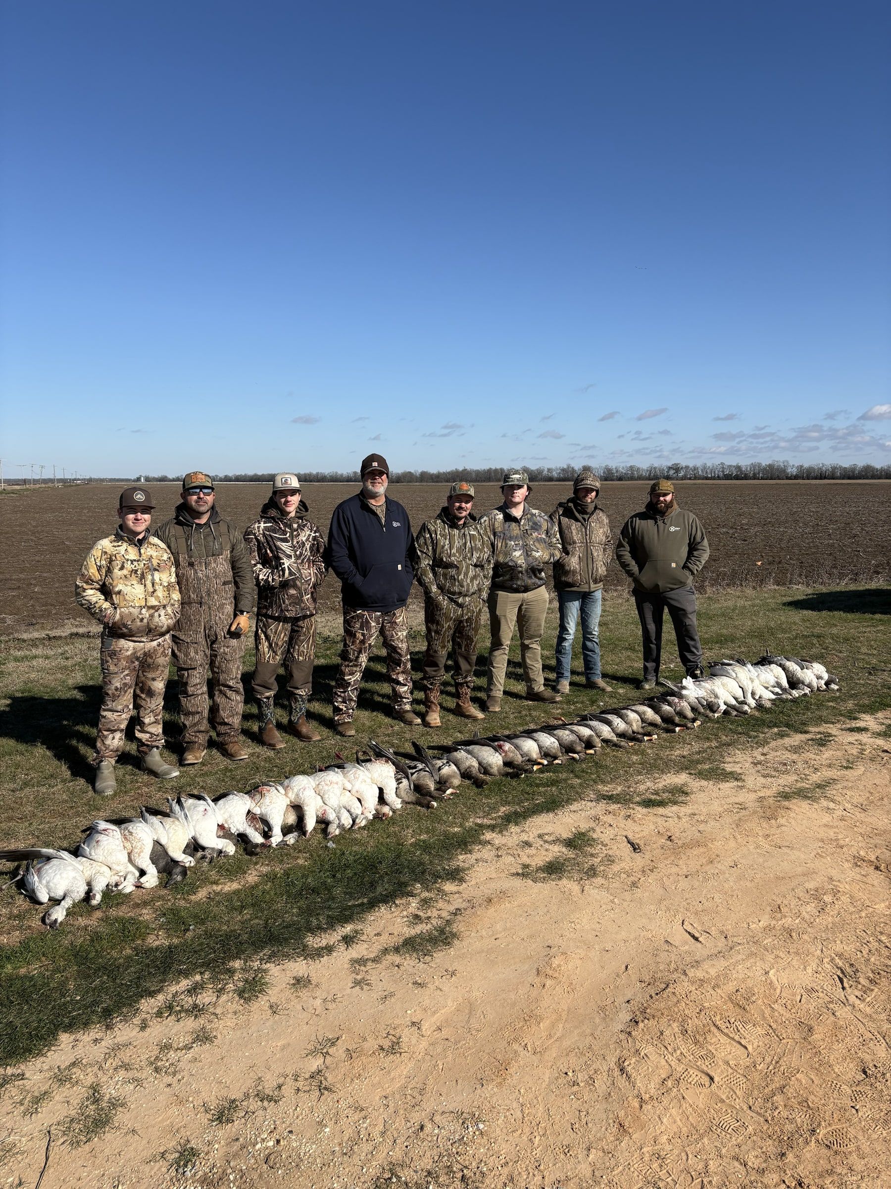 A Delta Outdoors hunting group standing beside a field lineup of specklebelly geese.
