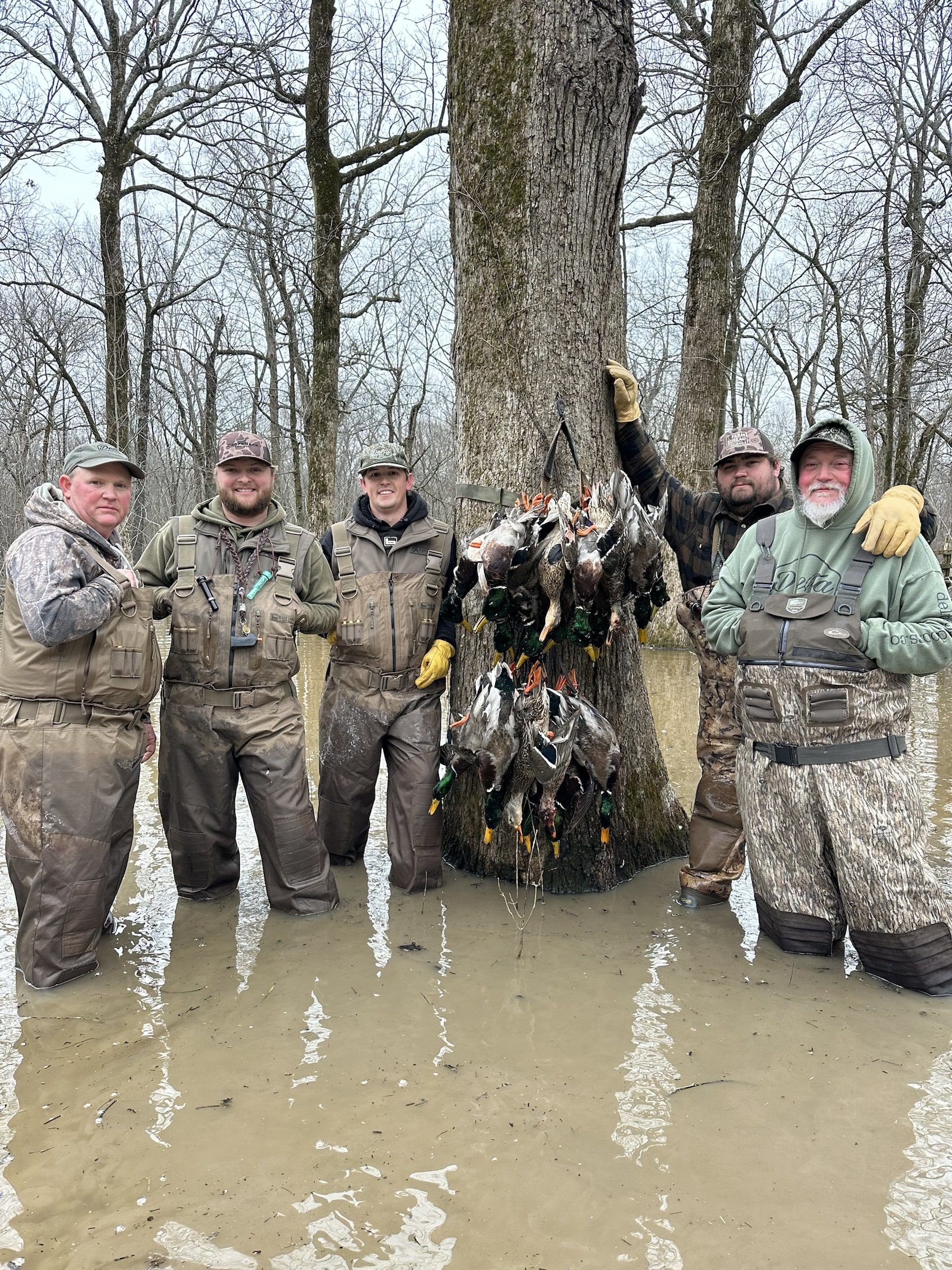 Delta Outdoors hunters standing in flooded timber with ducks after a hunt.